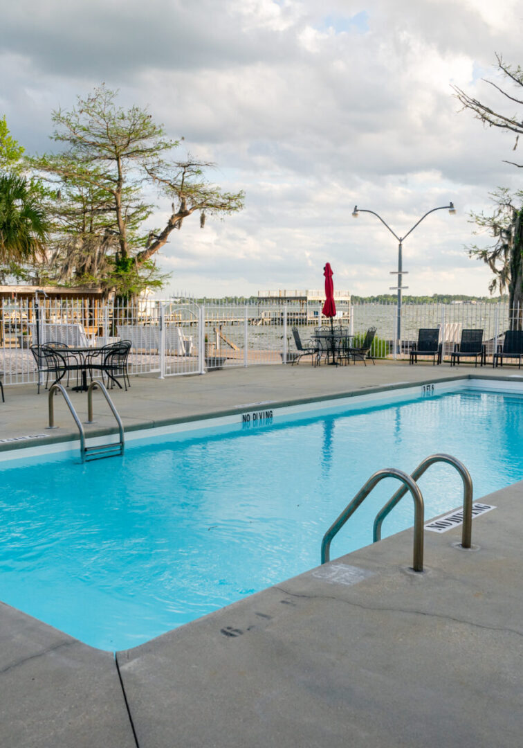 A pool with chairs and tables in the background.